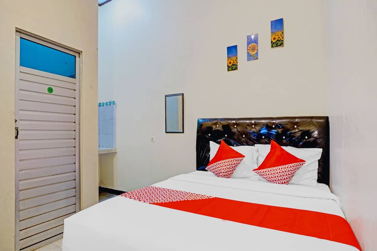 A hotel room with a bed, a closed door, and three wall-mounted pictures.
