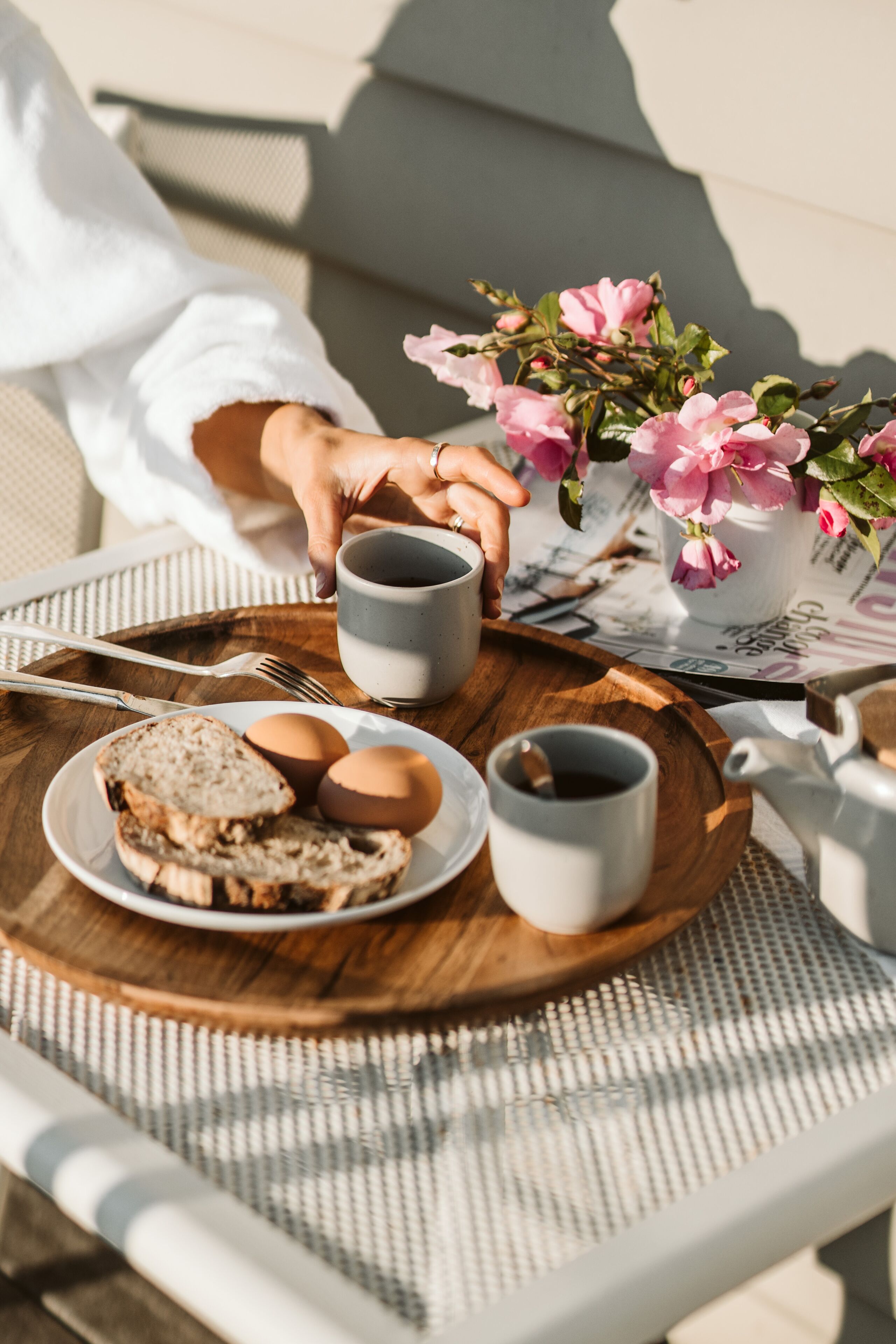 A breakfast tray with bread, eggs, and coffee cups on a woven table mat.