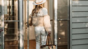 Une personne qui entre dans une maison moderne par une porte en verre.