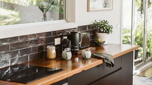 Une cuisine moderne dotée d’une grande fenêtre, de meubles de rangement aux couleurs sombres et d’un plan de travail en bois.