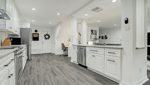 Una cucina moderna con mobili bianchi, elettrodomestici in acciaio inossidabile e un pavimento in legno grigio.
