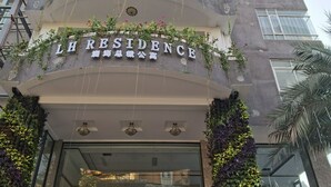 Hotellin sisäänkäynti, jossa on kyltti, jossa lukee ”LH RESIDENCE”, ja moderni muotoilu, johon kuuluu pystysuuntaisia viherseinäpuutarhoja.