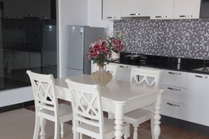 A modern kitchen with white cabinetry, a tiled backsplash, and a dining table with chairs.