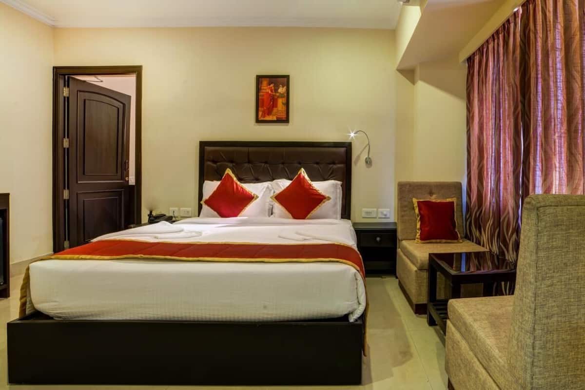 A hotel room with a large bed, two nightstands, a chair, and a curtain.