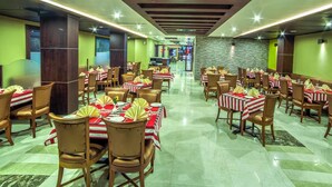 A restaurant with multiple tables and chairs, arranged in a spacious layout with a central aisle. - Chirag Inn (Thiruvananthapuram)