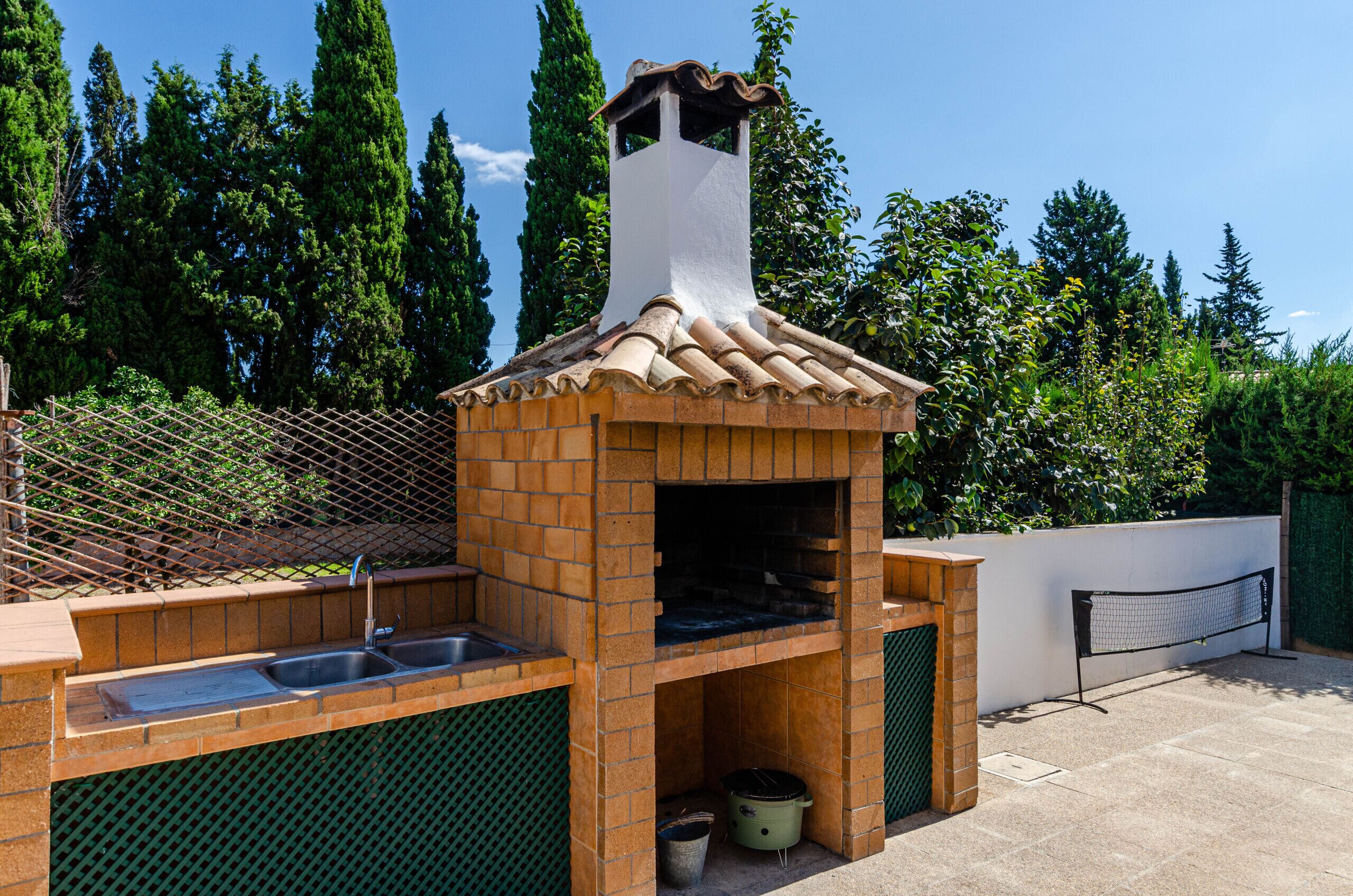 Un four en briques installé à l’extérieur, doté d’une cheminée, d’un évier et d’un espace barbecue.