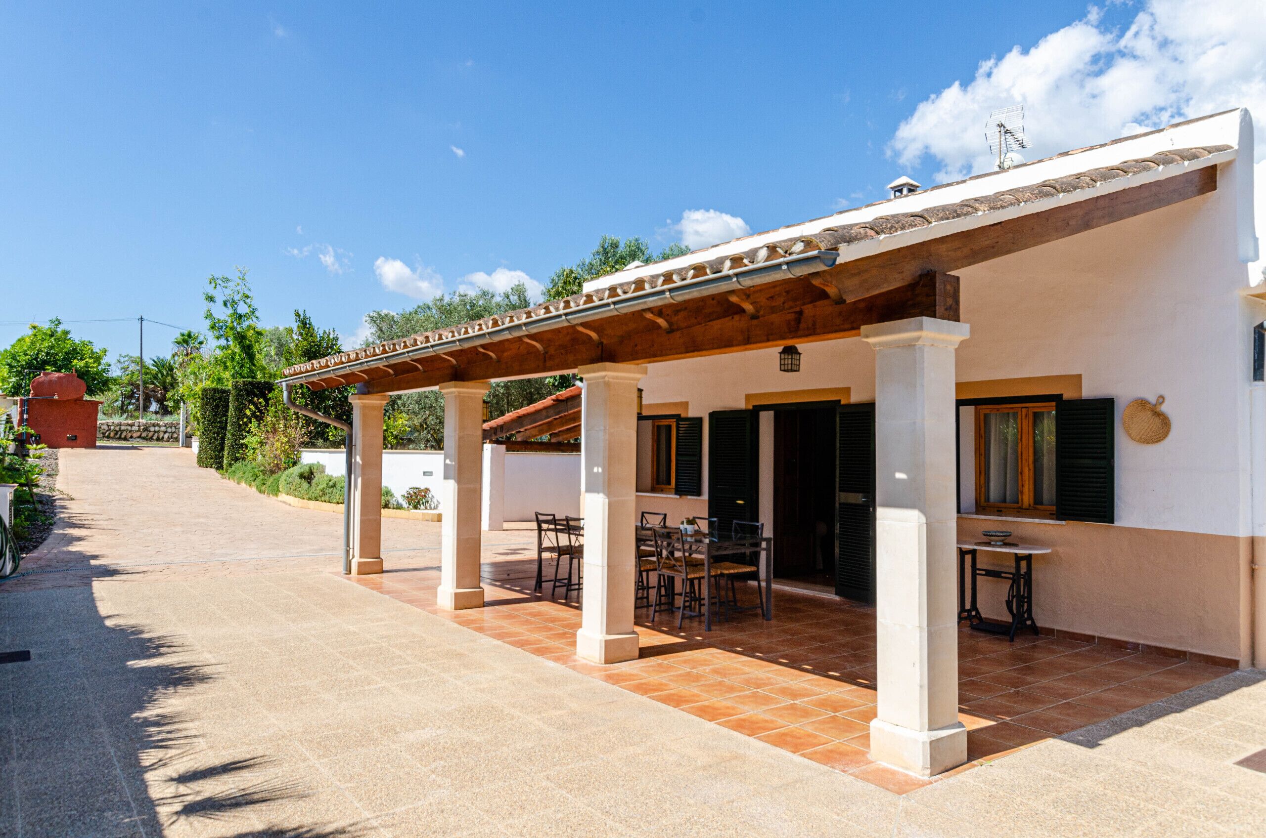 Une terrasse extérieure couverte, agrémentée d’une pergola, d’un espace salon et d’une petite table.