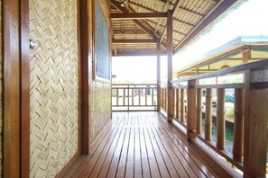 A wooden balcony with a woven wall and a metal railing. - Where2next Hostel (El Nido)