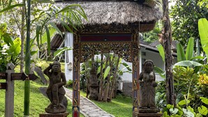A stone pathway leading to a thatched-roof structure with statues, surrounded by lush greenery. - Ubud Sari Health Resort (Ubud)