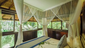 A bed with a canopy, a window with a view of greenery, and a wooden ceiling. - Ubud Sari Health Resort (Ubud)