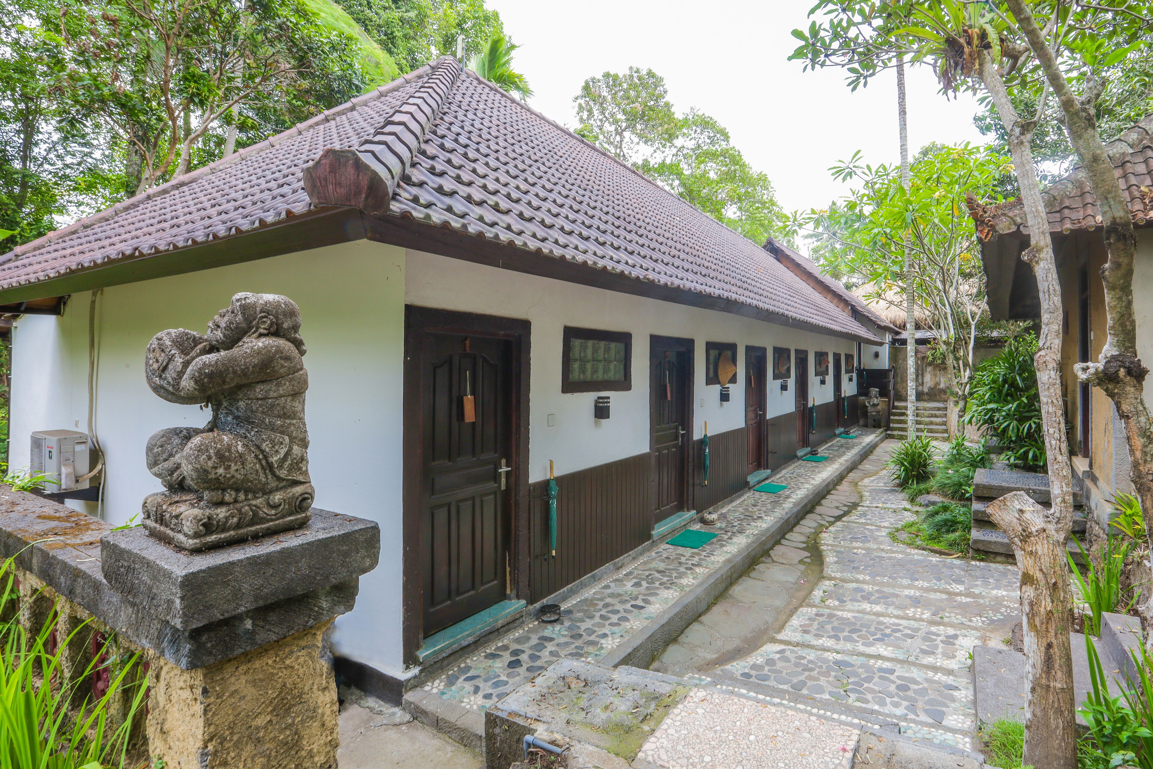 A traditional building with a tiled roof and a stone statue in front.