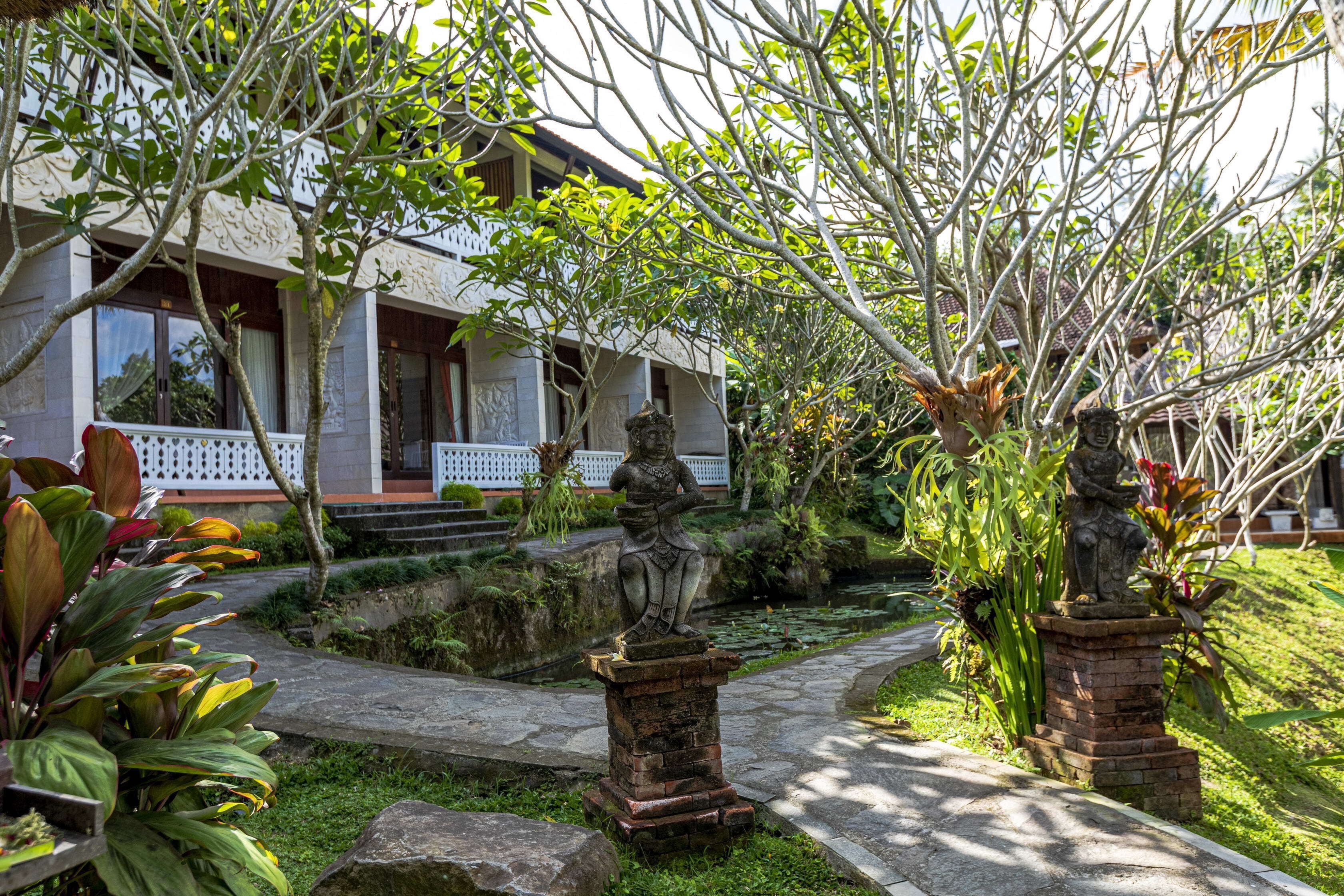 Una casa tradicional con un sendero en el jardín, una estatua y un estanque.