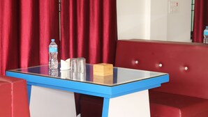 Une pièce avec une table à plateau en verre, une bouteille d’eau, des verres et une boîte de mouchoirs.