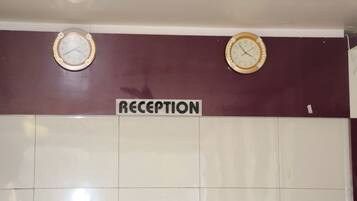Zona de recepción con dos relojes de pared y un cartel que dice "RECEPTION".