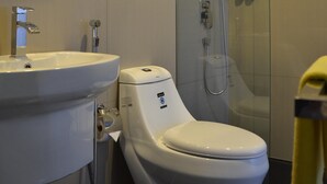 Une salle de bain avec des toilettes, un lavabo et une douche.