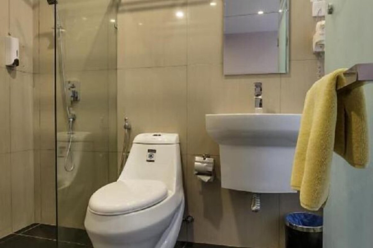 A modern bathroom with a glass-enclosed shower, a toilet, a sink, and a towel rack.