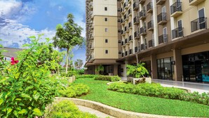 A modern apartment building with multiple balconies, a landscaped garden area, and a clear sky. - Azalea Suites Cikarang by Jayakarta Grup (Cikarang)