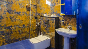 A bathroom with a marble wall, a white bidet, a sink, and a blue floor. - Habitat by Liwa (Bengaluru)