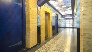 A hallway with blue doors, wooden walls, and patterned flooring. - Habitat by Liwa (Bengaluru)