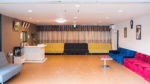 A reception area with a reception desk, a blue sofa, a yellow sofa, and a pink sofa. - Kanku Kokusai Hotel (Wakayama)