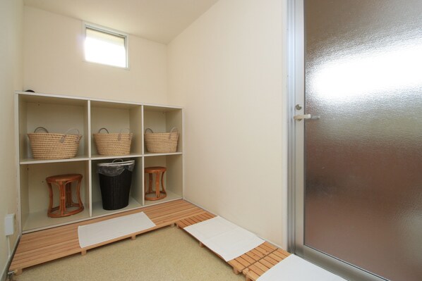 A room with a sliding door, a window, and a shelf with baskets and a trash bin.