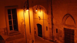 Un pasillo tenuemente iluminado con arcos y un ave posada en la barandilla.