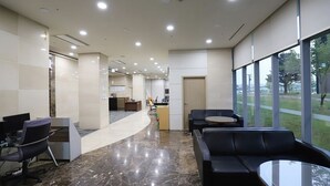 A modern lobby with a curved reception desk, seating area, and large windows offering a view of the outdoors. - Daejeon I-Hotel (Daejeon)