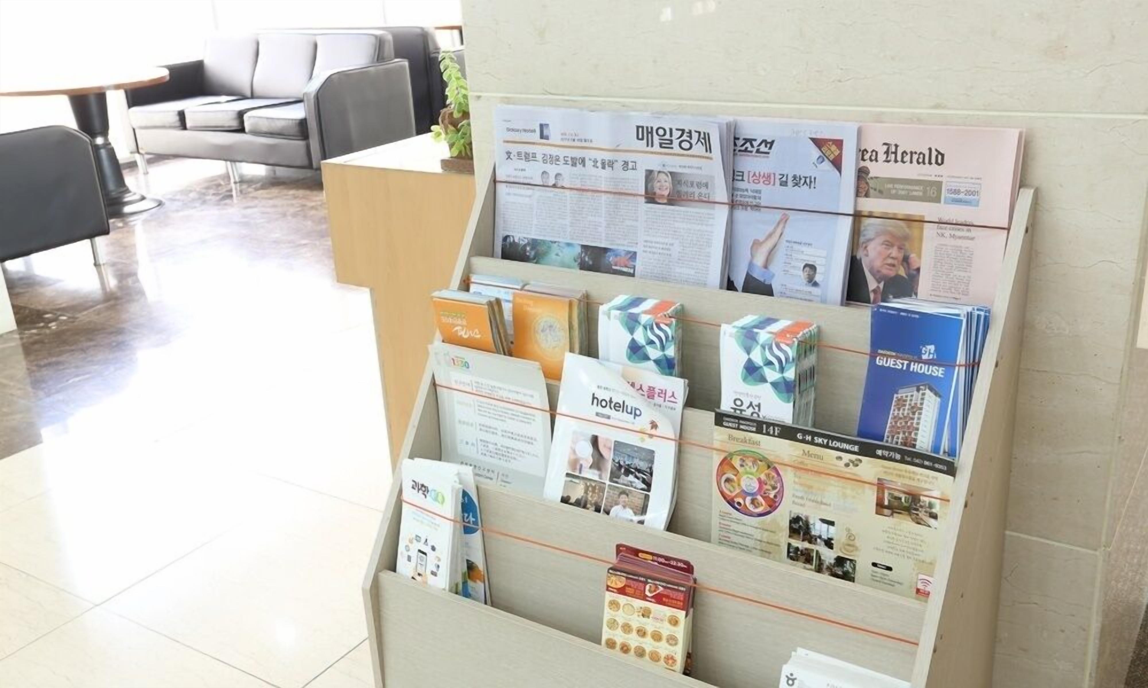 A reception desk with brochures and pamphlets for hotel services, including a 'hotelup' sign and a 'GUEST HOUSE' brochure.