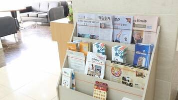 A reception desk with brochures and pamphlets for hotel services, including a 'hotelup' sign and a 'GUEST HOUSE' brochure.