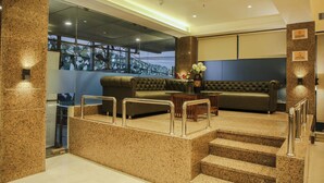 A lobby with a staircase, a sofa, a coffee table, and a flower vase. - Hotel Citrus Prime (Raipur)