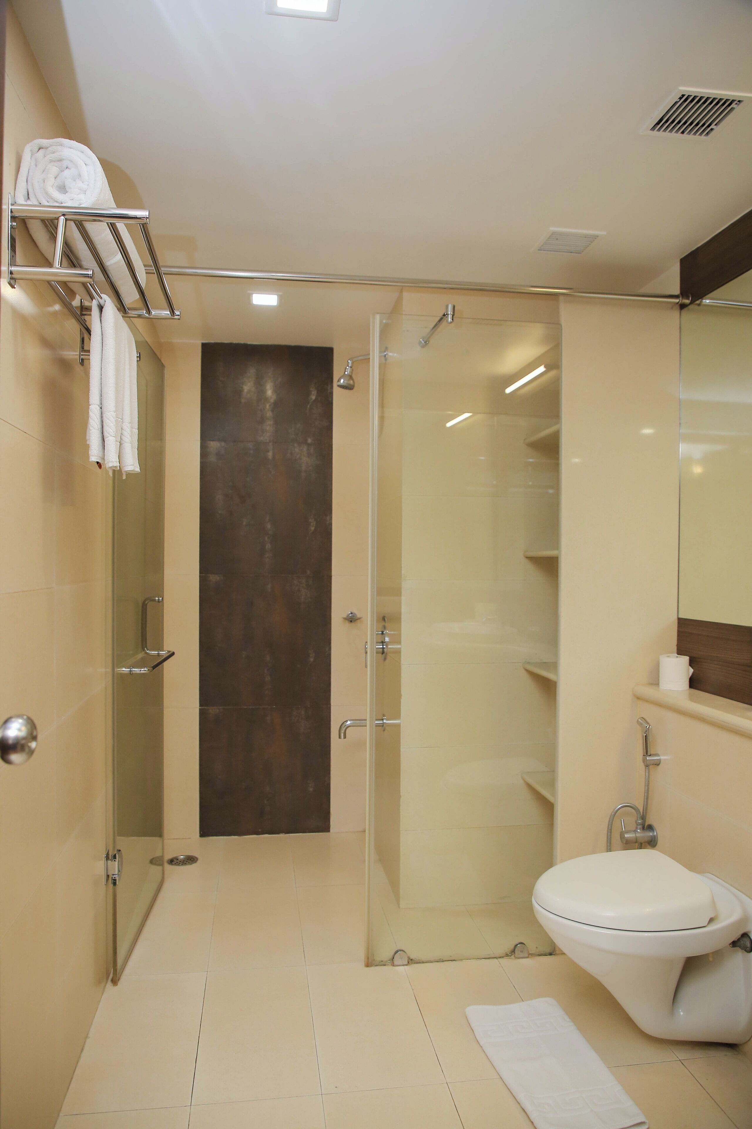 Un baño moderno con ducha de vidrio, un inodoro y un perchero para toallas.