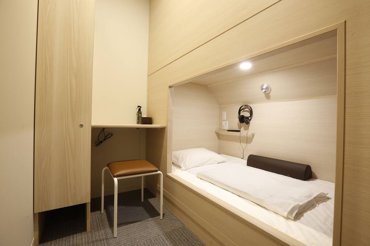 A compact room with a single bed, a small desk, and a chair.