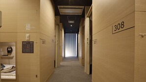 Un pasillo de hotel con paredes de madera, puertas numeradas y piso alfombrado.