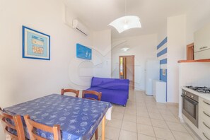 A compact living space with a dining area, kitchenette, and a bed.