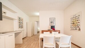 A modern kitchen with white cabinets, a tiled backsplash, and a dining area with a white table and chairs. - Two-room apartment with sea view near the famous Sansone beach (Portoferraio)