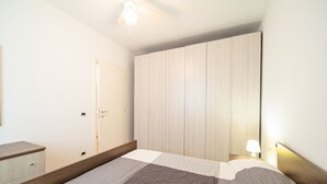 A bedroom with a bed, a wardrobe, a bedside table, and a ceiling fan. - Two-room apartment with sea view near the famous Sansone beach (Portoferraio)