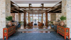 A lobby with stone walls, wooden beams, and a central seating area with sofas and a coffee table. - Shinta Mani Mustang (Jomsom)