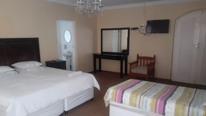 Une chambre d’hôtel avec deux lits, un bureau, une chaise, une télévision et un lustre.