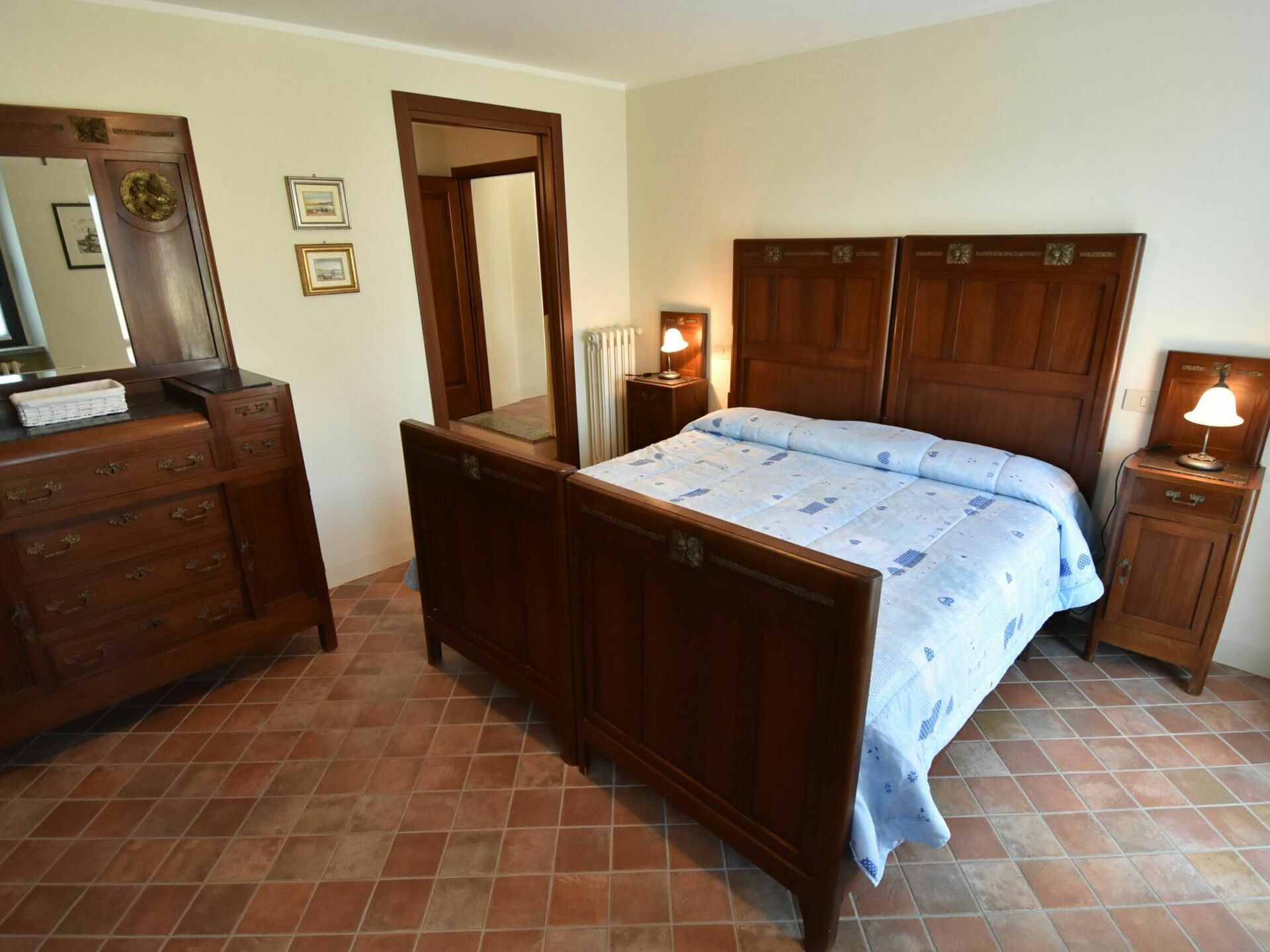 Un dormitorio con una cama de madera, un aparador, un espejo y dos lámparas de noche.
