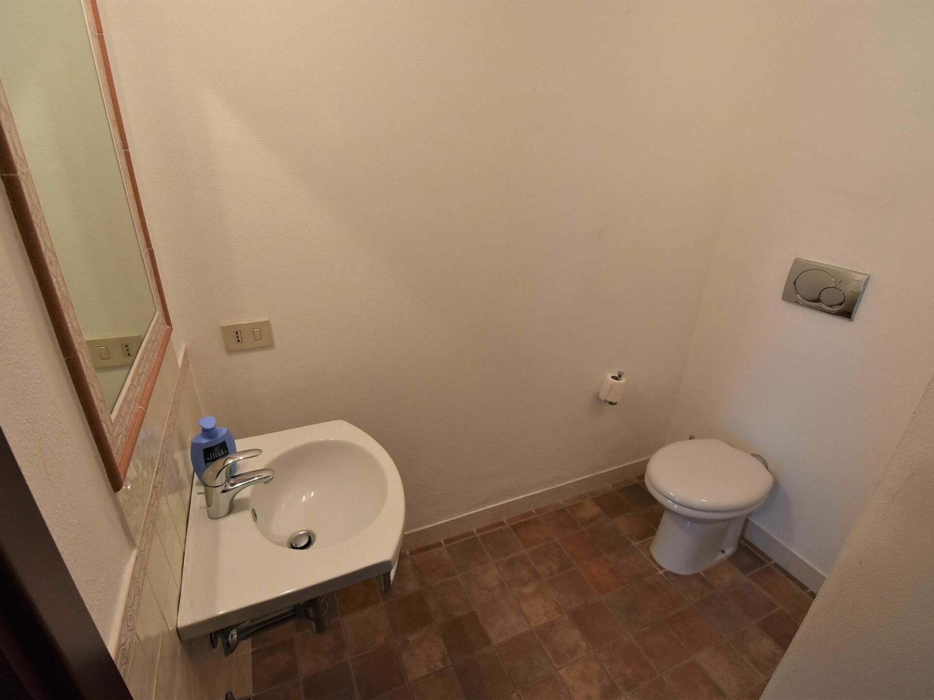 Une petite salle de bain avec un lavabo blanc, des toilettes et un miroir.