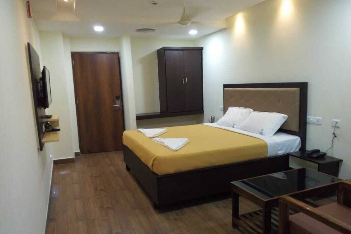 A hotel room with a bed, a desk, a chair, a wardrobe, and a television.