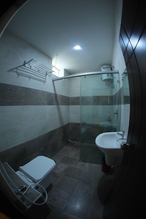 Un baño con inodoro, lavamanos y cabina de ducha de cristal.