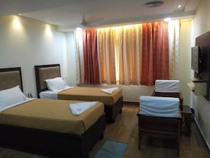 Habitación de hotel con dos camas, un escritorio, una silla y un televisor.