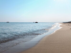 A beach with calm waters and a clear sky.