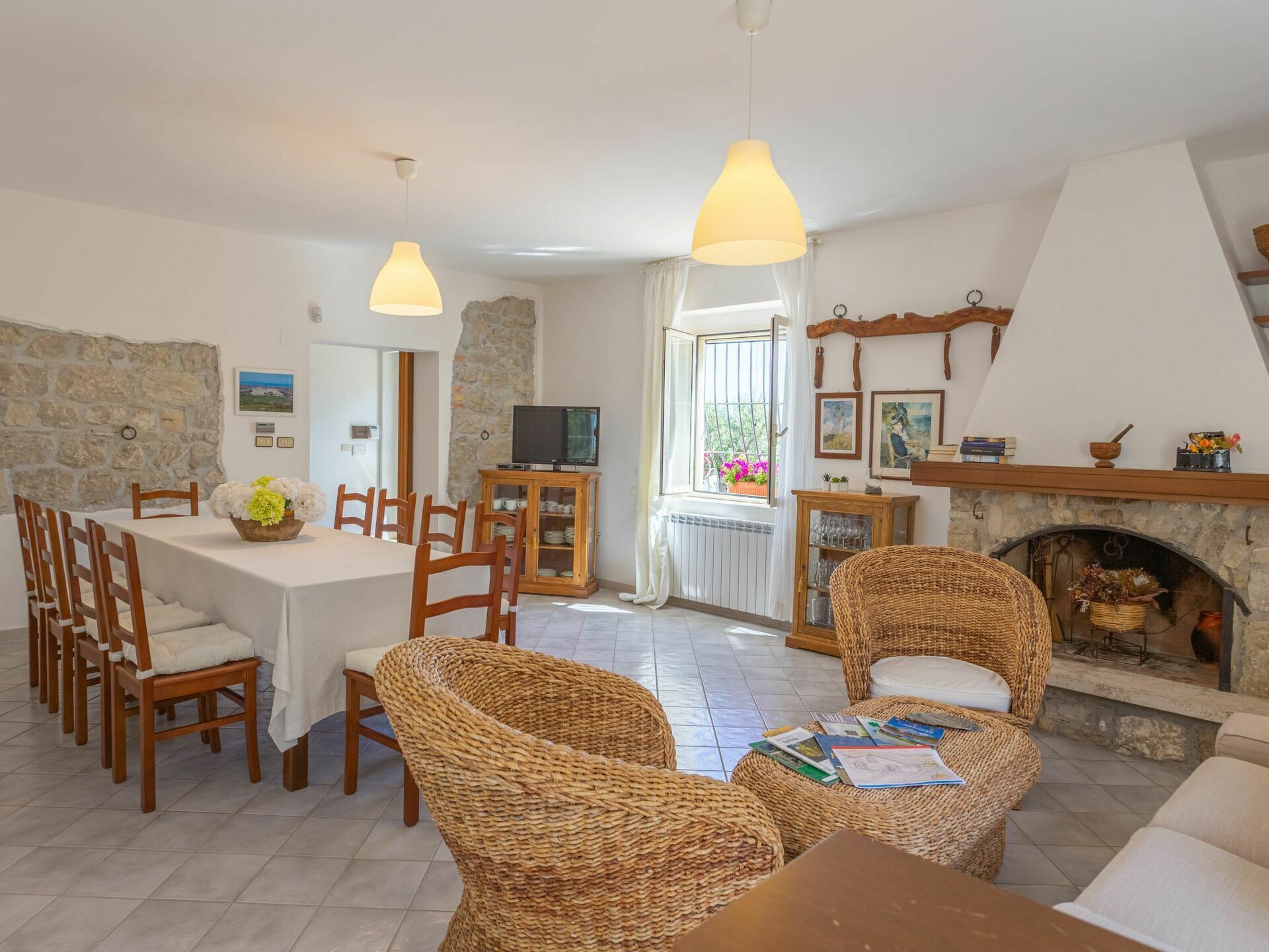 Una sala de estar acogedora con chimenea, comedor con mesa y sillas, y un televisor sobre un mueble.