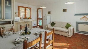 A dining area with a table set for four, a sofa, and a refrigerator. - Wonderful private villa for 4 people with WIFI and TV (Massa)