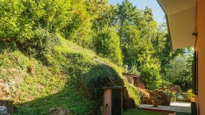A garden with a small structure, a stone wall, and a wooden bench. - Wonderful private villa for 4 people with WIFI and TV (Massa)