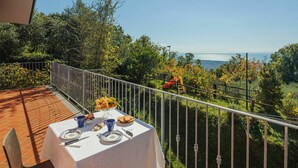 A terrace with a table set for breakfast, overlooking a scenic view of trees and the sea. - Wonderful private villa for 4 people with WIFI and TV (Massa)