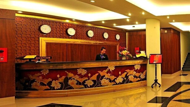 Un comptoir d’accueil avec un panneau décoratif en bois, plusieurs horloges et un motif floral.