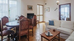A living room with a round table, chairs, a sofa, a television, and a chandelier. - Cosy apartment for 6 people with WIFI, TV, patio and pets allowed (Montignoso)